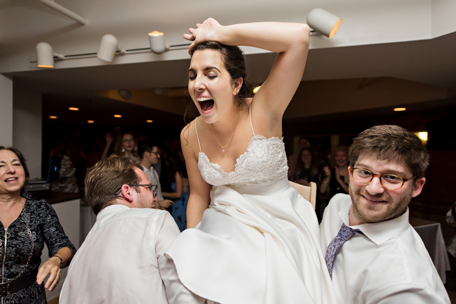 A bride lifted in the air on a chair at her wedding reception.